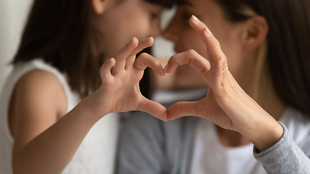 Child And A Mother Forming A Heart From Fingers