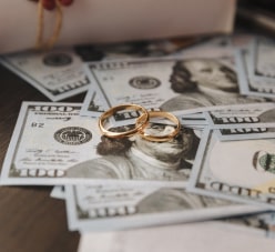 100 Dollar Bills And Two Gold Rings On Top Of Them